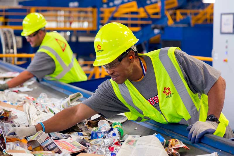 Man separating plastic recyclables on conveyor belt